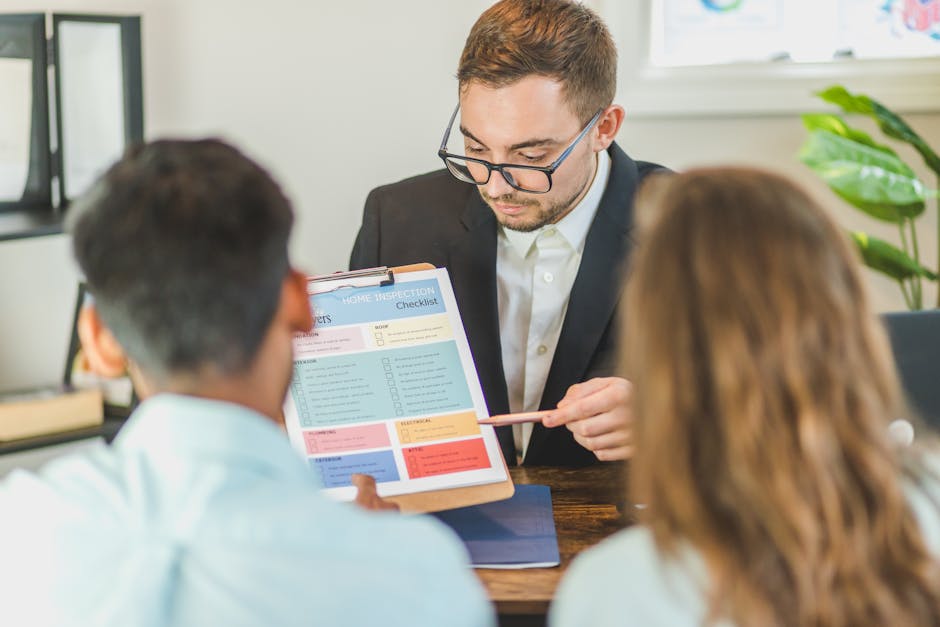 A professional waste management specialist in a dark suit, wearing glasses, holds a clipboard with a detailed home inspection checklist while discussing with two clients seated at a wooden table. The clipboard displays a colour-coded list of tasks, including categories like 'cleaning,' 'repairs,' and 'waste removal,' with tick boxes for completion. The individuals are indoors in a well-lit, modern office environment, with a large window allowing natural light to illuminate the scene. A potted plant with broad green leaves is visible in the background, adding a touch of greenery to the professional setting. The specialist appears focused and informative, supporting the context of estate clearance or home assessment relevant to waste disposal and rubbish removal services provided by companies like House Clearance Pimlico. The scene emphasizes the importance of thorough planning for property clearance, including sorting, categorizing, and managing waste efficiently, ensuring compliance with disposal standards and proper waste handling in an urban setting.